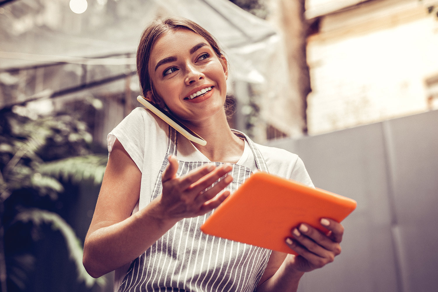 woman smiling on the phone with ipad in hand