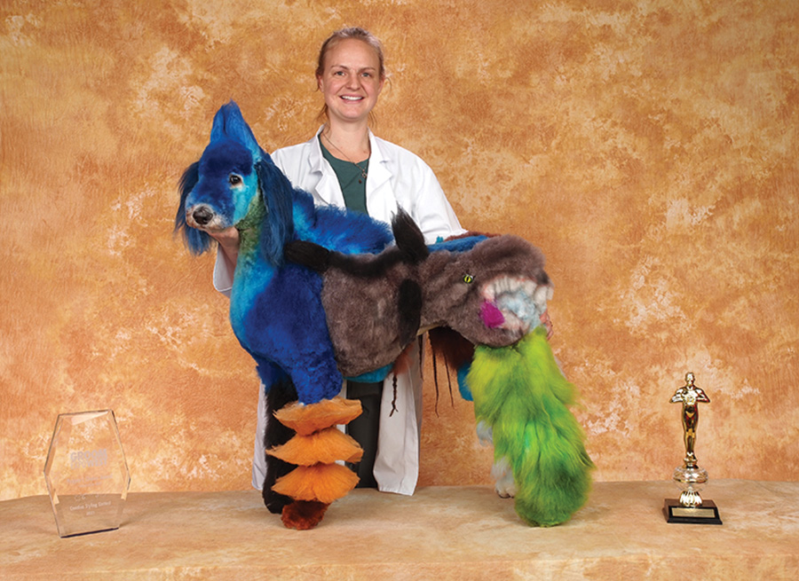 Madeline Rothwell with a styled dog with dyed ornag, blue, green fur and the ANDIS Sponsor