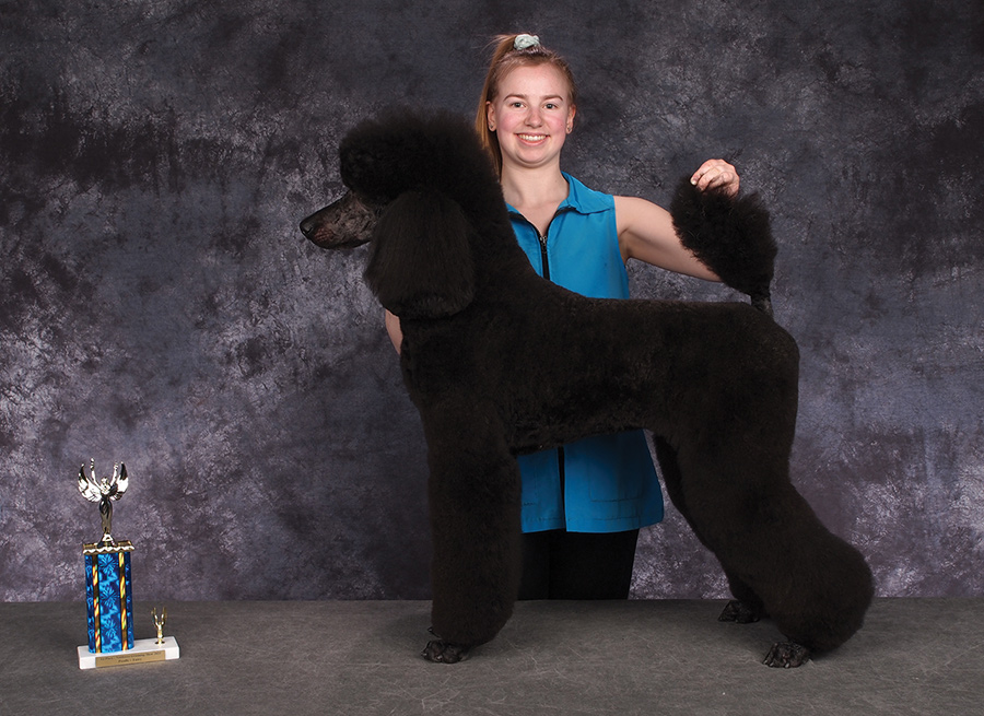 Shannon Wegner posing with a black poodle 
