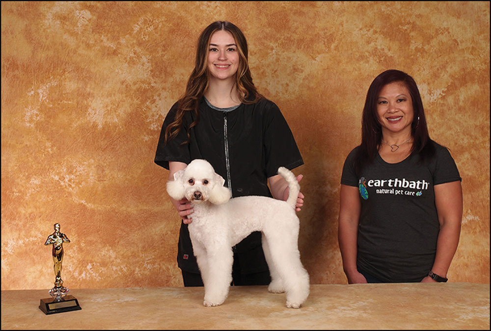 Two women standing with groomed dog