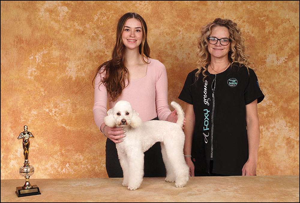 Two women standing with groomed dog
