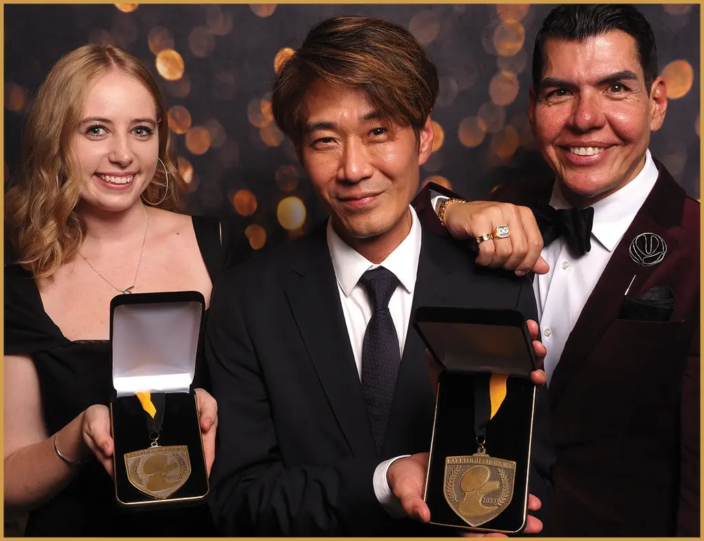 One woman and two men holding up awards and smiling