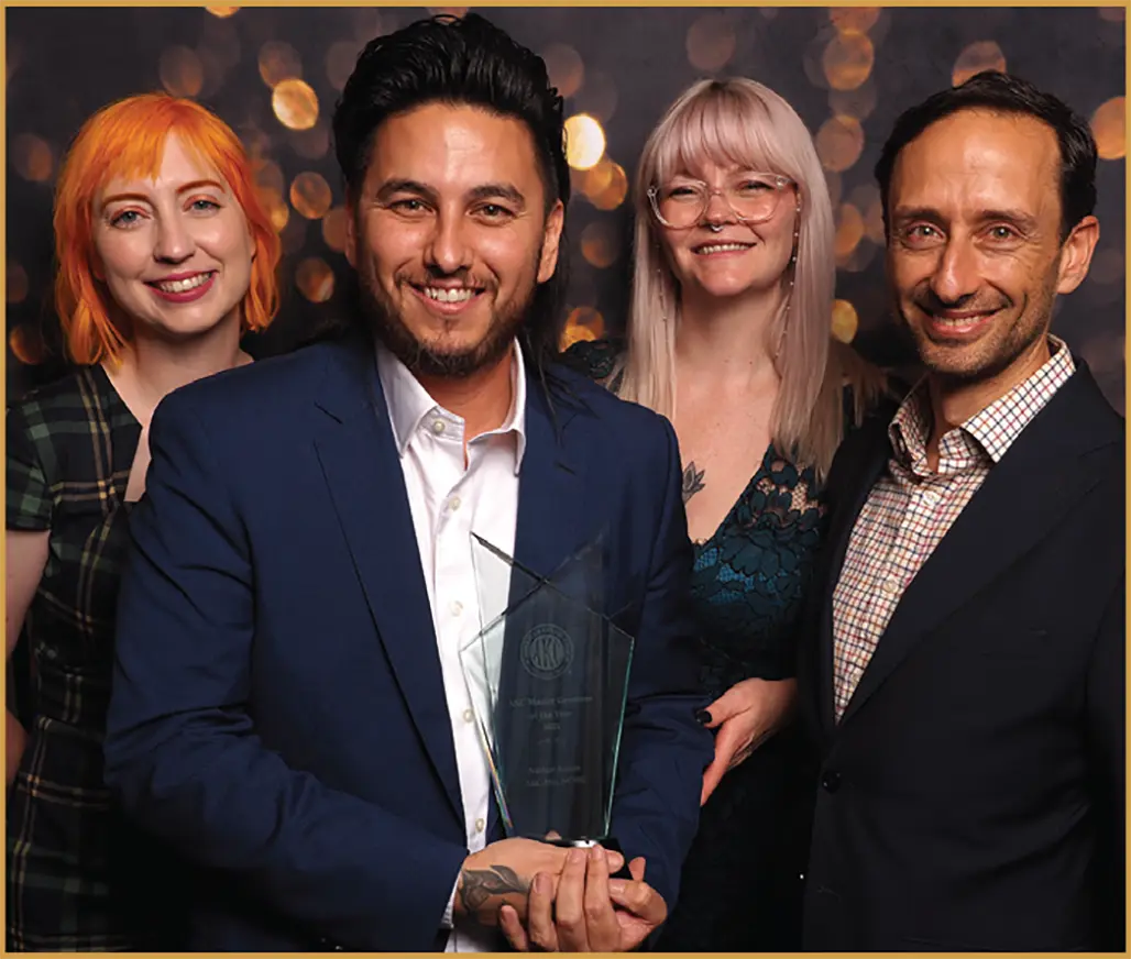 Nathan Austin hold ups an award alongside two women and another man as they all smile together