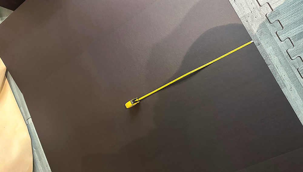 Close-up landscape photograph perspective of a small yellow ruler being measured halfway across the Black Tri-fold Foam Presentation Board