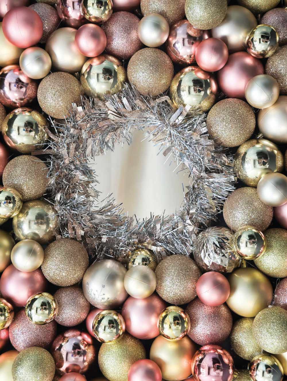 Close-up portrait photograph perspective of an assorted bigger bunch of Ornaments glued around the dark/light bronze Garland/Tinsel with a cut-out circular hole through it with shiny lighted reflections off the Ornaments