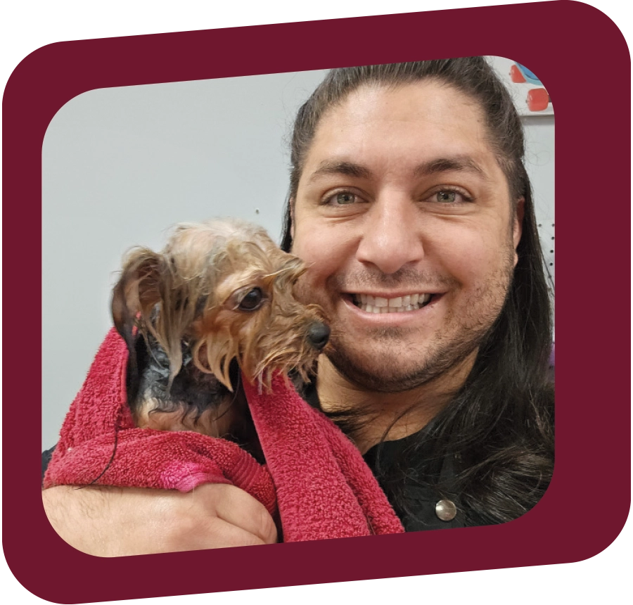 man holding a small dog in a red towel after a bath while smiling
