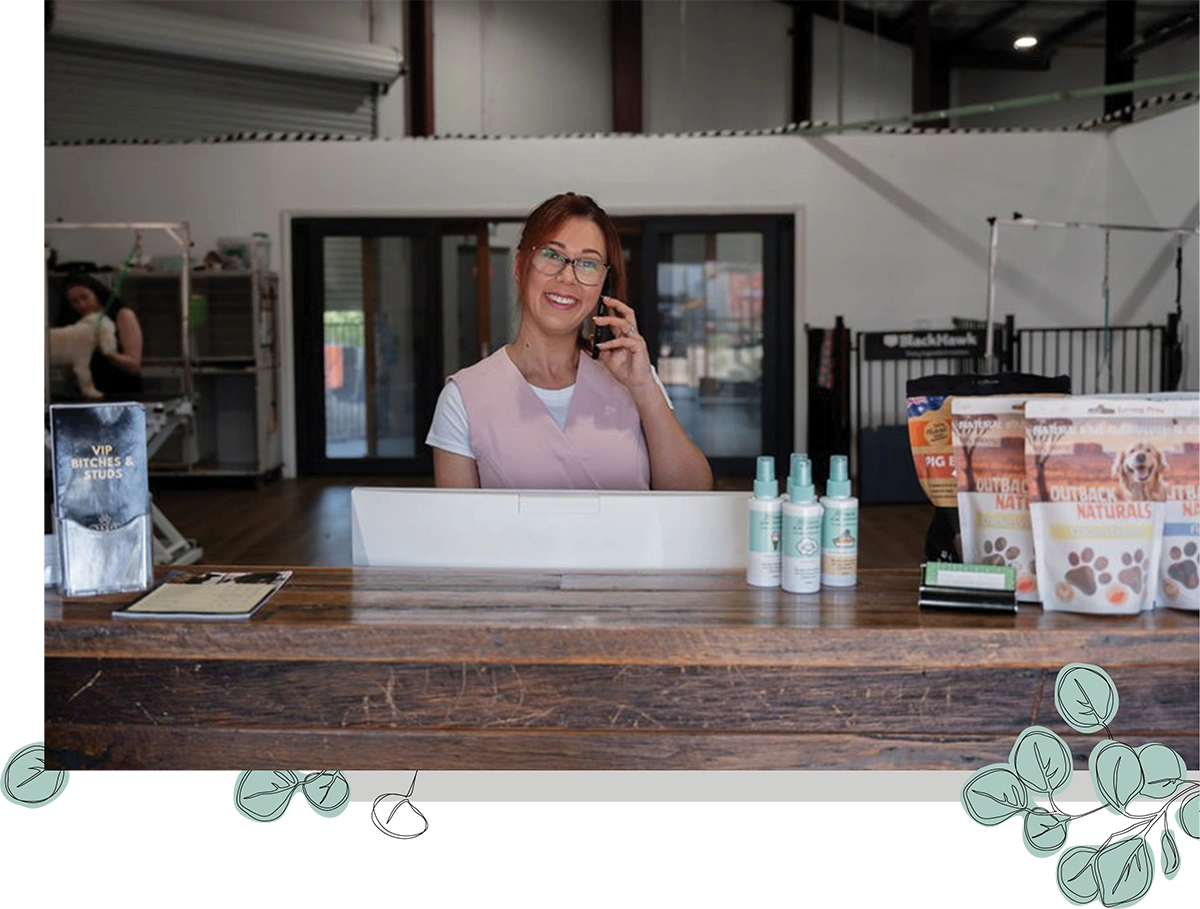 woman smiling while on the phone at the front desk of a groomer business