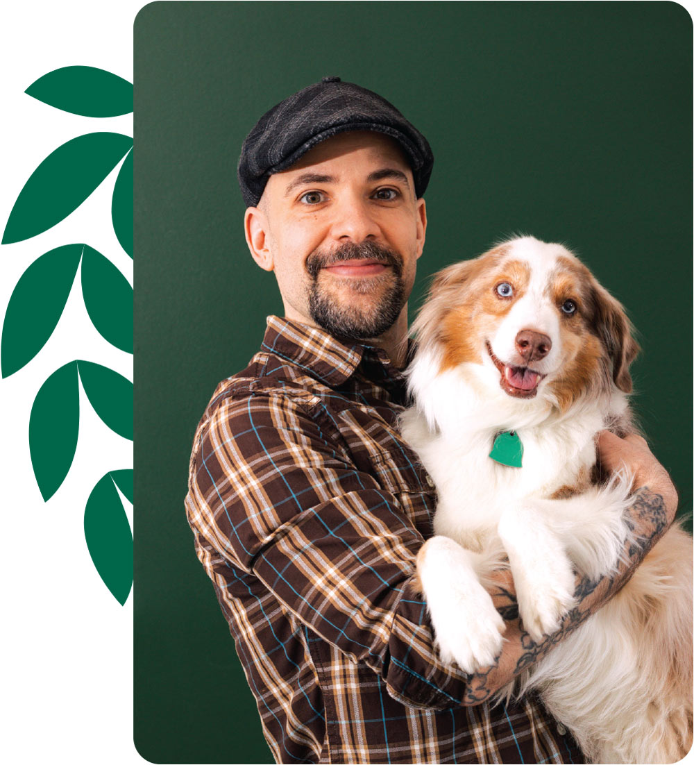 Grooming Arts Northwest founder Karu Wojtaszek smiles while holding a full sized Australian Shepherd in both arms