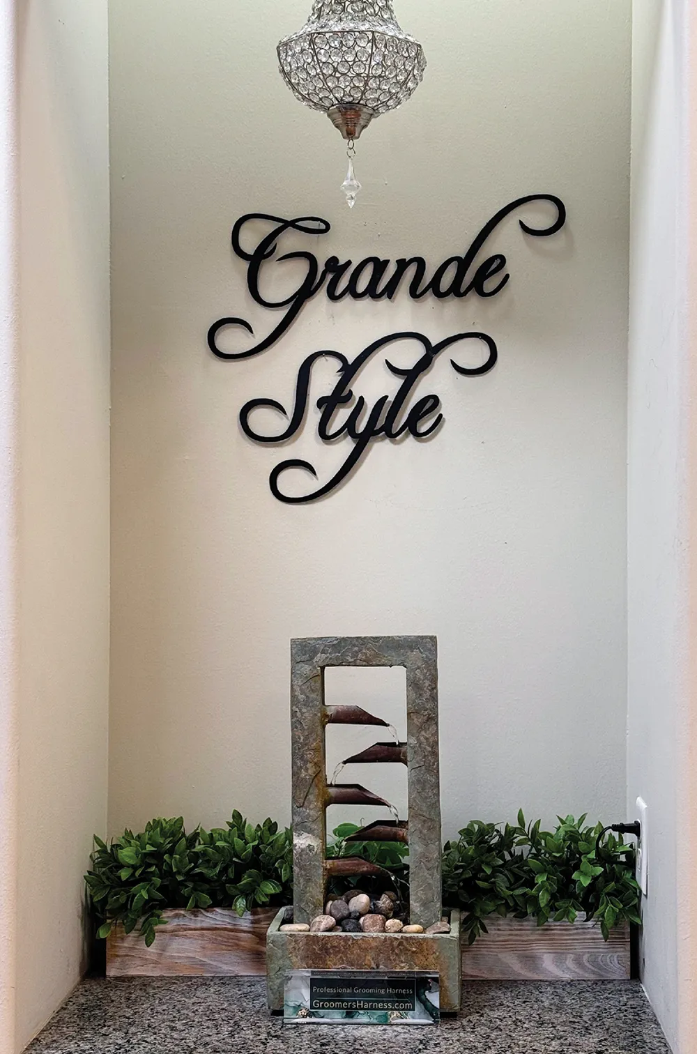 Decorative niche with 'Grande Style' text, stone fountain, and green plants.