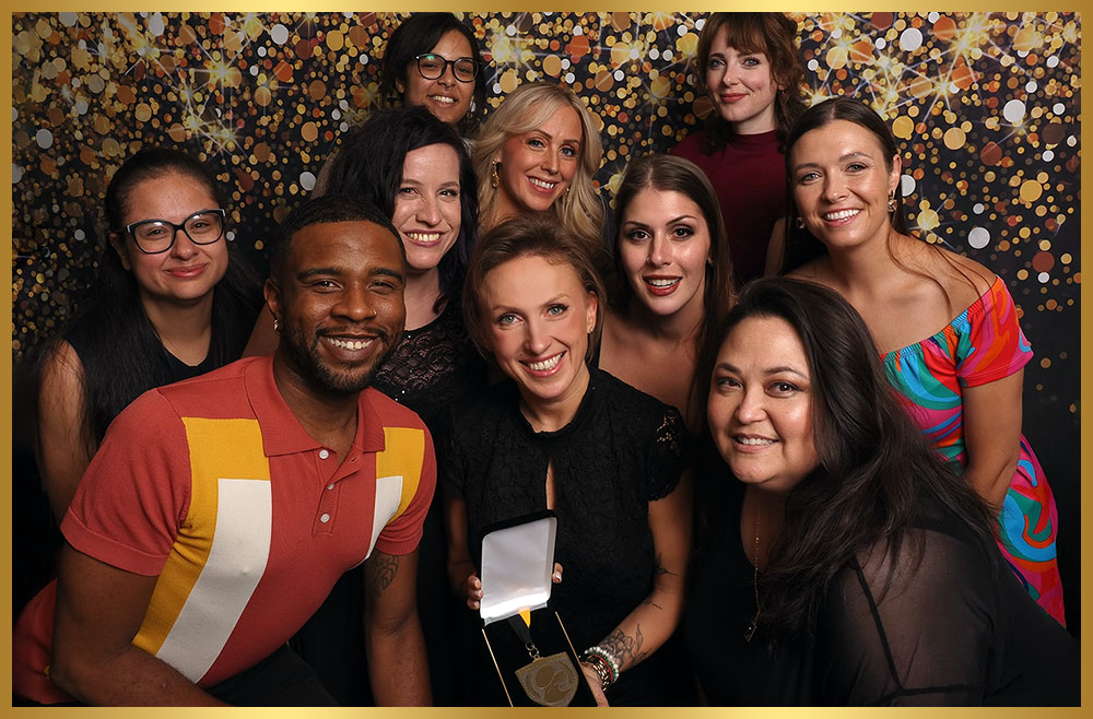 ten representatives of Botaniqa take a group photo as the centeral representative holds a medal in a presentation box