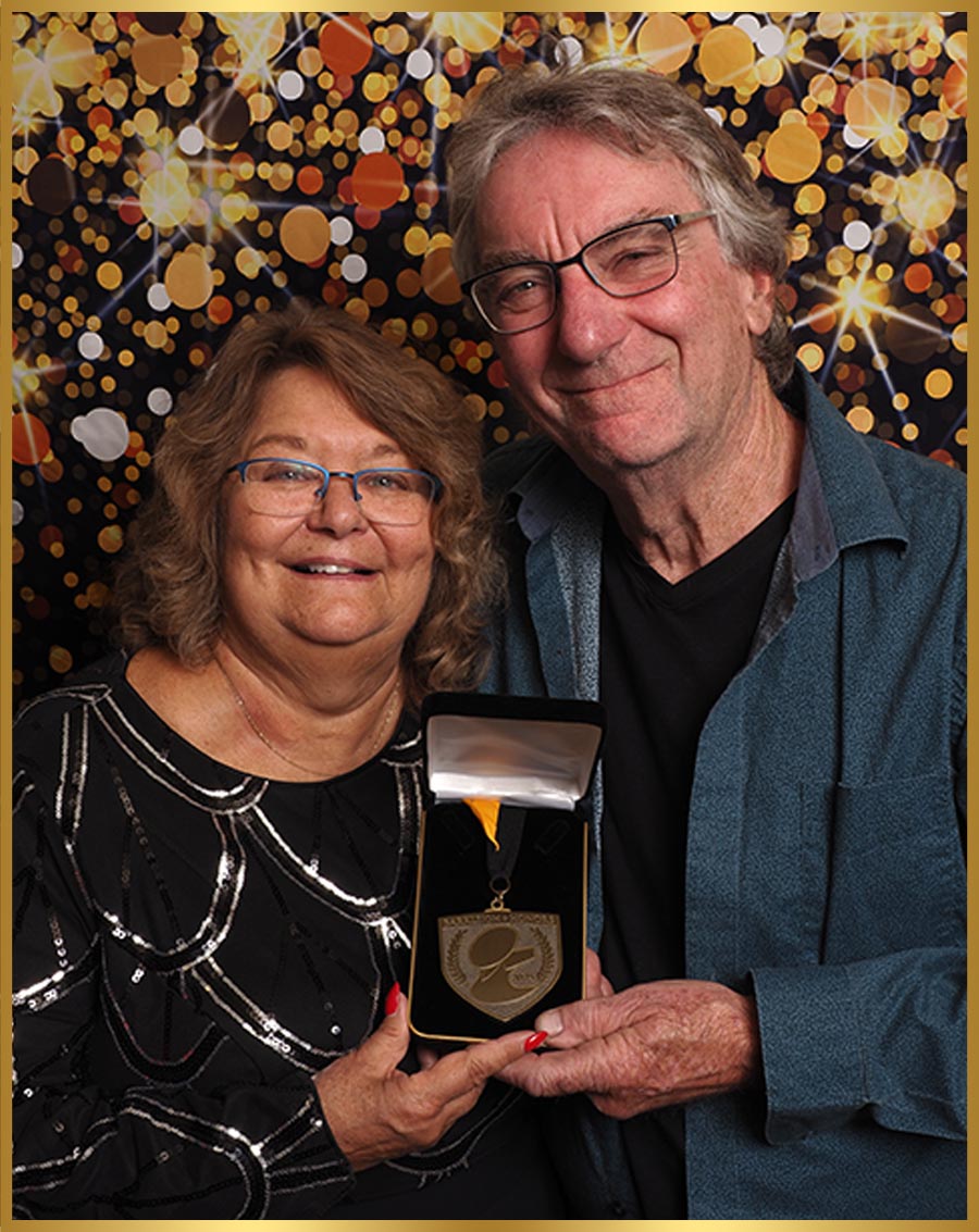 two Precision Sharp representatives take a photo while both holding a medal in a presentation box