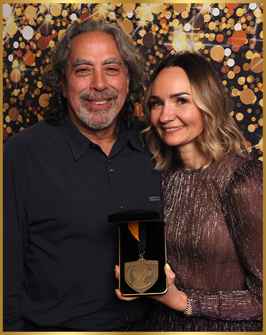 a man and a woman from Pet Store Direct take a photo together as the woman holds a medal in a presentation box