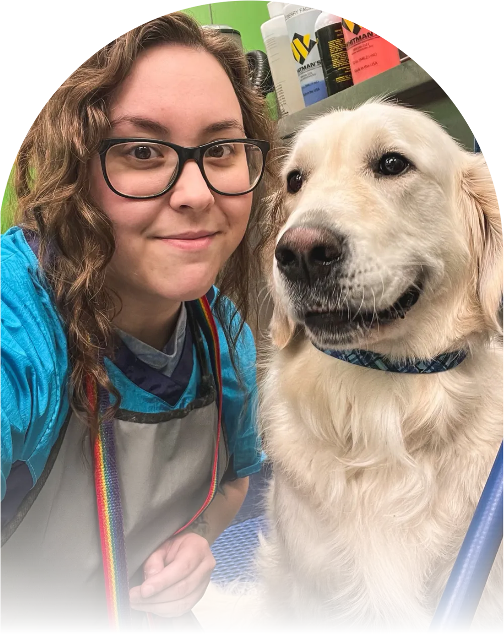 A female groomer takes a selfie with a smiling Golden Retriever.