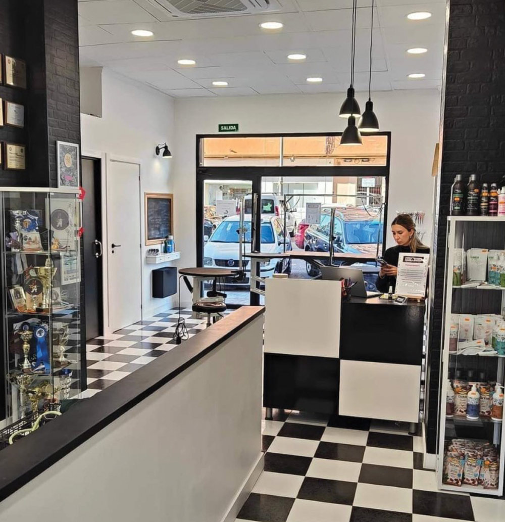 Wide interior shot of the Mary Groom reception and retail area. Features a black and white checkered floor, a sleek front desk, and glass display cases filled with trophies.