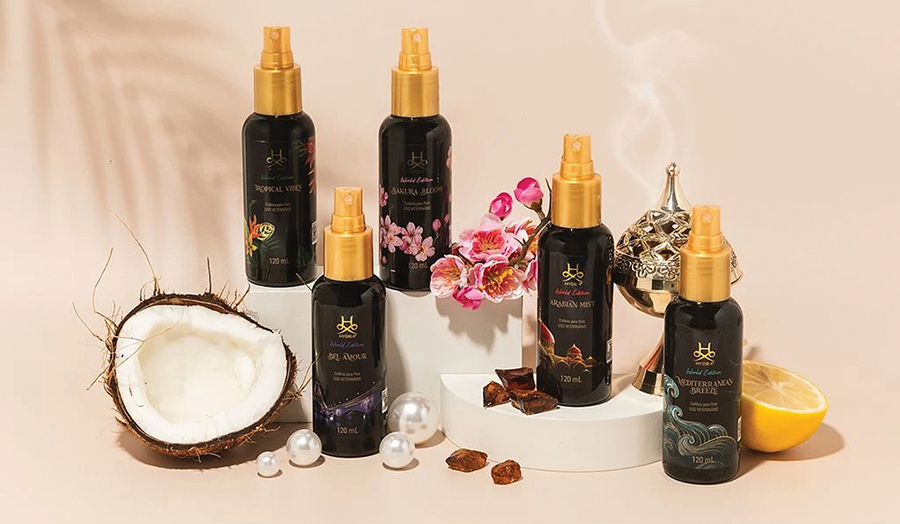 Hydra cologne spray bottles surrounded by decorative props like coconut, flowers, and lemons.