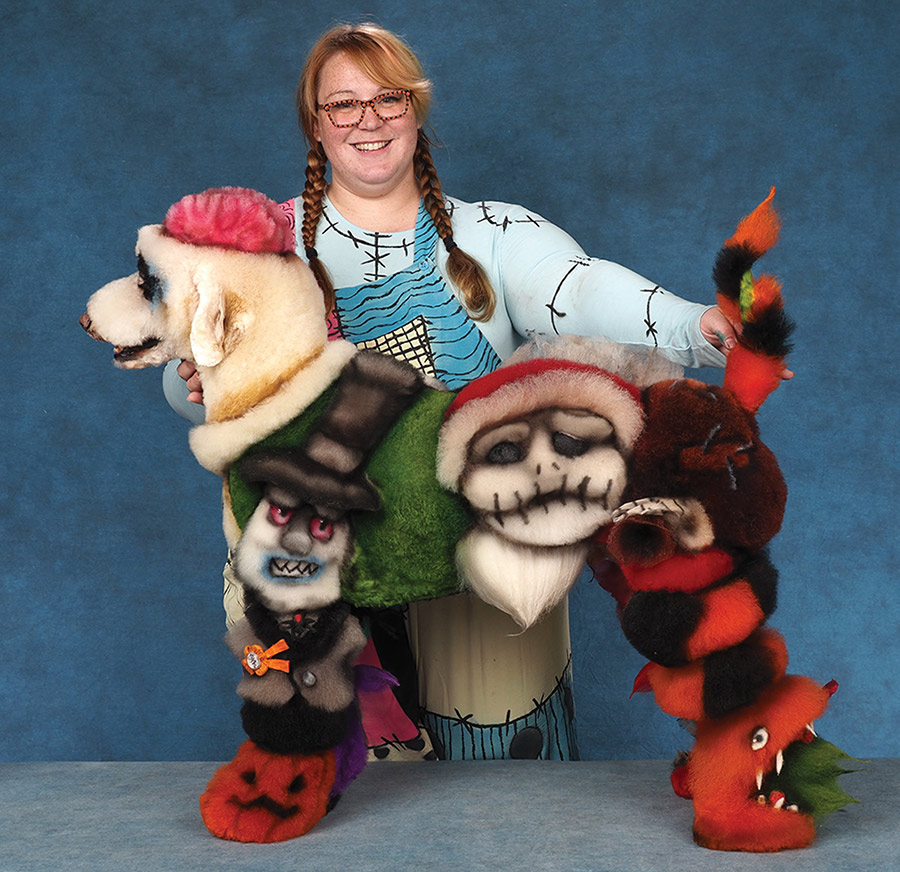 A woman in a costume holds a Standard Poodle creatively groomed with The Nightmare Before Christmas character designs.